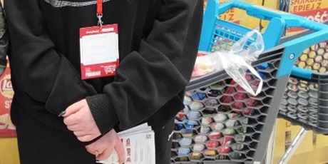 Powiększ grafikę: Dziewczynka stoi w sklepie spożywczym  podczas akcji zbiórki żywności