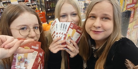 Powiększ grafikę: Nauczycielka i dwie dziewczynki stoją w sklepie spożywczym  podczas akcji zbiórki żywności