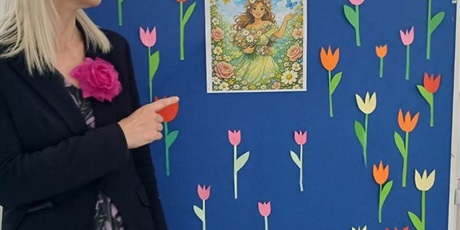 Powiększ grafikę: „Nauczycielka prezentuje gazetkę ścienną z kolorowymi tulipanami i hasłem ‘Wiosna na Zielonym’.”