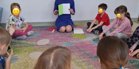 Powiększ grafikę: Nauczycielka prowadzi zajęcia wielkanocne w świetlicy, dzieci siedzą w kręgu i słuchają poleceń