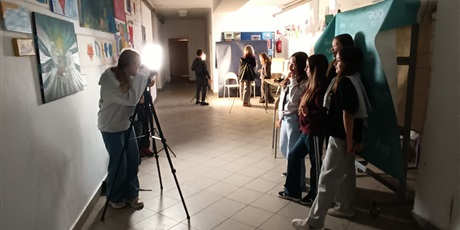 Powiększ grafikę: „Grupa uczennic pozuje do zdjęcia w szkolnym korytarzu podczas sesji fotograficznej z użyciem lamp i statywu.”